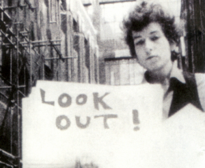 Bob Dylan holding "look out" card