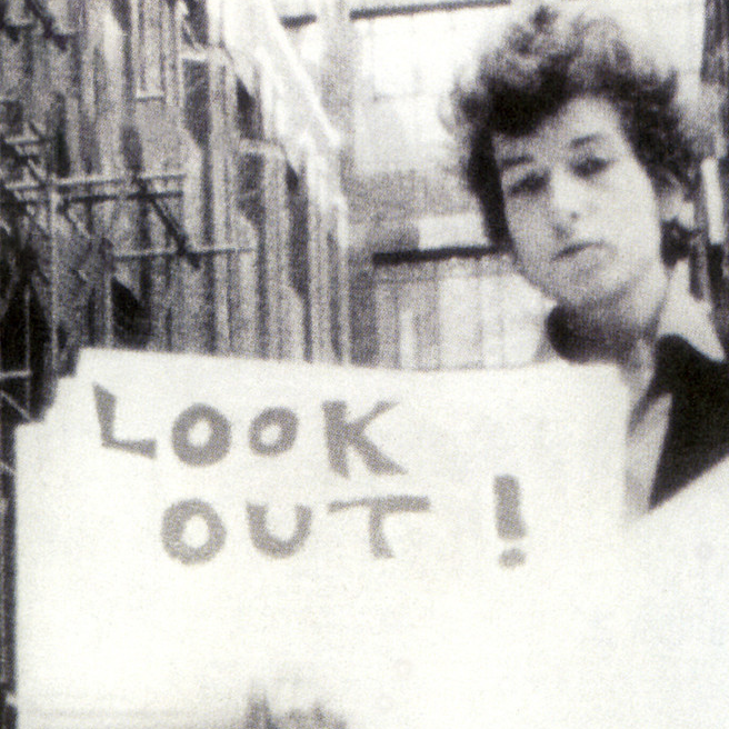 Bob Dylan holding "look out" card